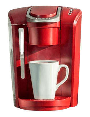 A traditional, bulky red coffee maker with a cup of coffee positioned under its spout, representing the older generation of brewing technology that is stationary and requires a power source. The machine's size and reliance on an electrical outlet contrast with the portable and convenient design of the modern FLEX brewing system.