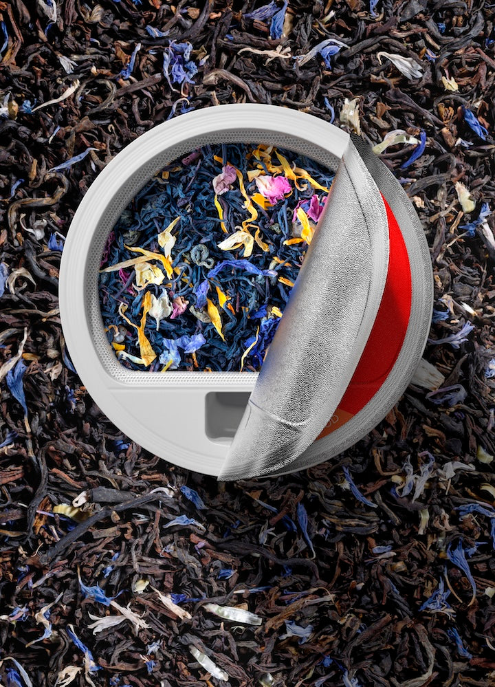 Top view of a filter basket filled with loose-leaf Earl Grey tea, featuring dried blue cornflowers and orange peels among black tea leaves, showcasing the natural and vibrant ingredients of the FLEX tea line.